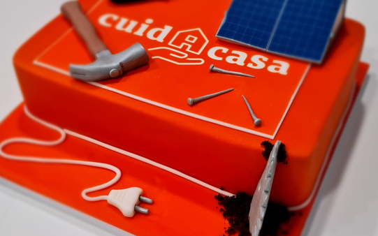 ¡Qué dulce sorpresa nos han traído a Cuidacasa! 🍰🧡 Nos han obsequiado con un pastel corporativo de color naranja, decorado con martillos, clavos y placas solares. ¡Es realmente chulo!